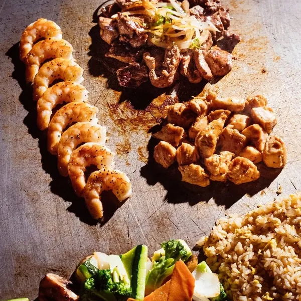 Hibachi steak, chicken and shrimp cooking with vegetables