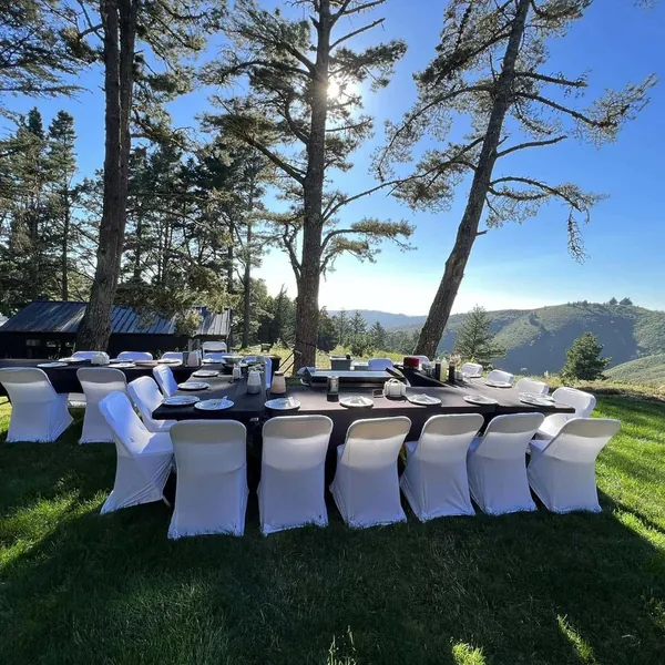 Outdoor hibachi party tables with white chair covers on a lawn